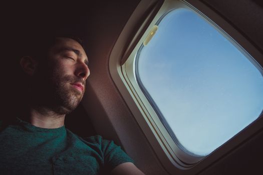 Young man resting and sleeping on an airplane.