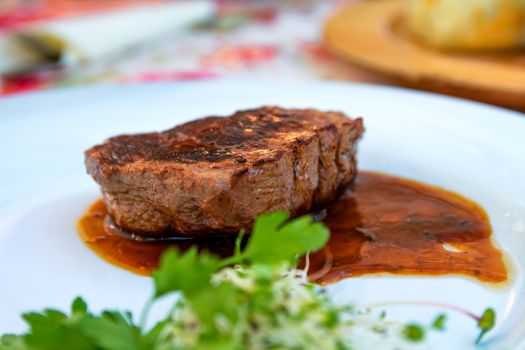 Grilled steak beef with sauce served on a white plate. Close up selective focus.