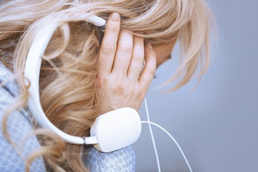 Blond woman listening music via headphones