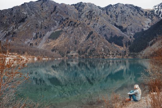 Woman listening music at the water's edge of mountain lake