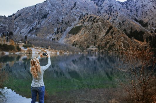 Woman making mobile photo at the mountain lake