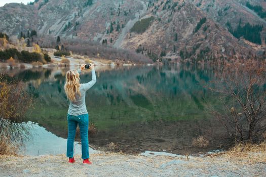 Woman making mobile photo at the mountain lake