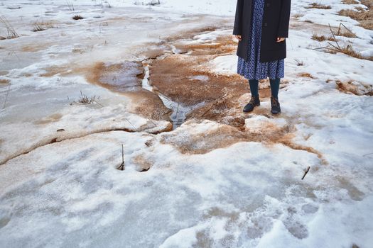 Woman standing at the puddle in winter landscape
