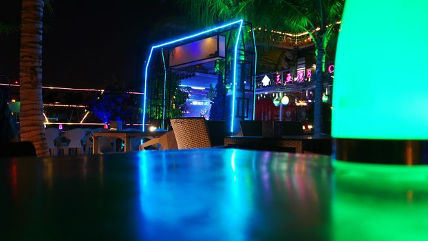 Night club, bar, cafe. Tropical beach club bar at night with purple, green, blue lights