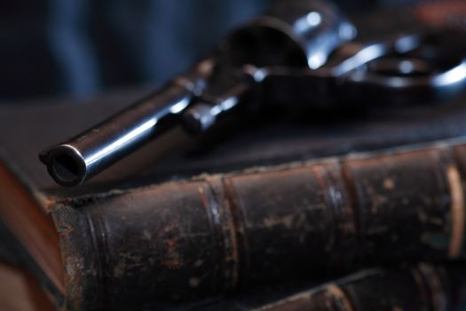 Vintage still life. Old handgun on book against dark background