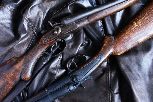 Pair of ancient hunting shotguns closeup on leather background