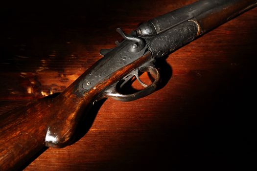 Ancient hunting shotgun closeup on wooden background