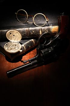 Vintage still life with revolver and spectacles near old books