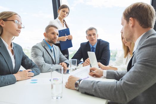 Mixed group of white collar workers in business meeting discuss documents