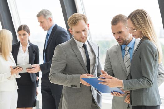 Successful business team discussing documents and ideas standing