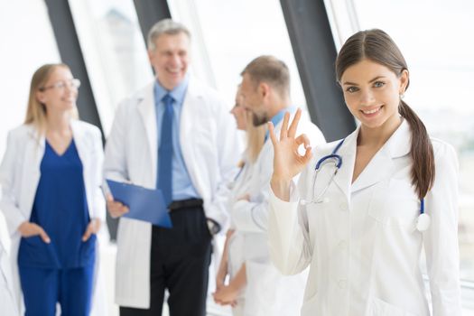 Female doctor showing Ok sign , team of doctors on background