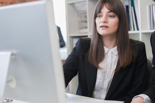 Business woman sitting in front of computer and looking at its screen