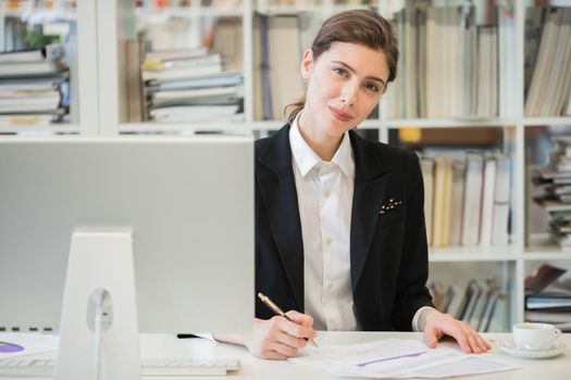 Portrait of business woman working with financial documents and computer