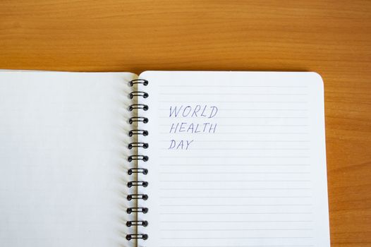 Notepad with text world health day on wooden table, health concept, minimalism style copy space.