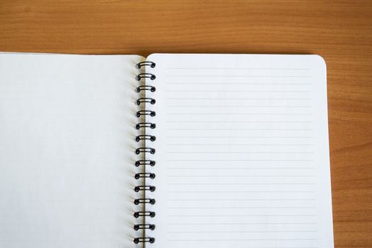 Empty open Notepad for writing, lies on a wooden brown table, top view, minimalism style.