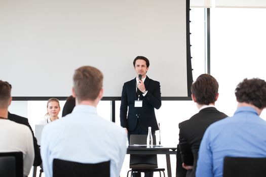 Speaker at business conference near white screen and audience