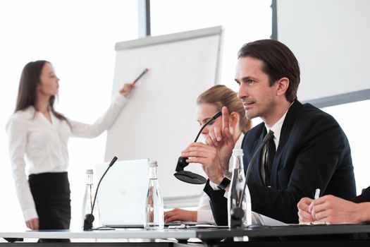 Group of speakers at business meeting at the table with microphones