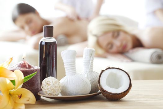 Spa massage tools and women getting massage on background