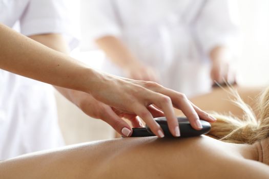 Young beautiful woman in spa getting hot stone massage