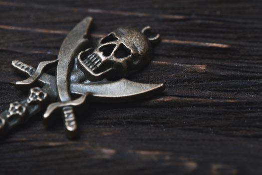 Vintage skull and pirate key on a wooden table. Close-up view