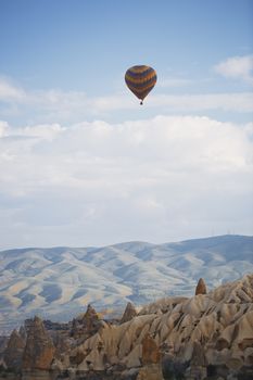 Hot air balloon flying over the rocky land. Cappadocia, Turkey