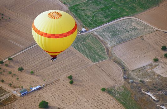 Yellow hot air balloon flying over the land