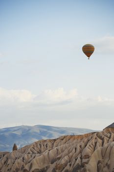 Hot air balloon flying over the rocky land. Cappadocia, Turkey