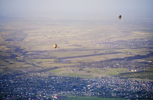 Hot air balloons above the green field and villages