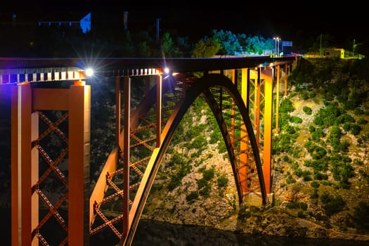 Illuminated bridge at night, steel arch construction, light trails of cars, old Maslenica bridge near Zadar, Croatia