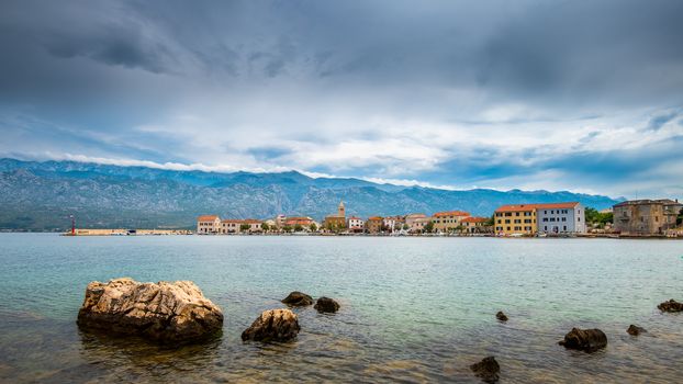 Traditional old village Vinjerac, Croatia, Velebit mountains and Paklenica national park in background, dramatic sky clouds, panorama, beach with rocks in front, copyspace