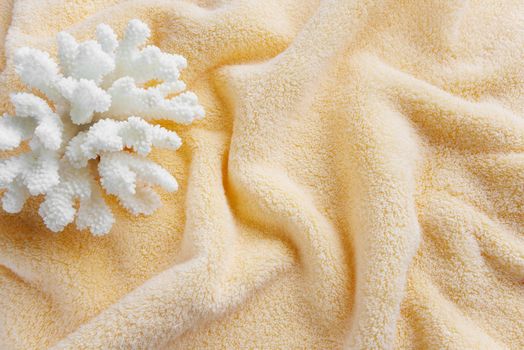 Beautiful white sea coral on the background of cotton terry orange towel, crumpled by waves