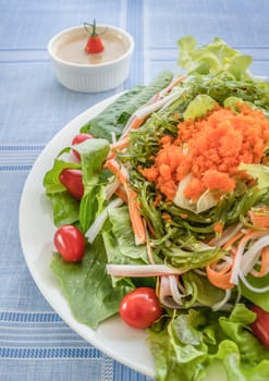 fresh organic salad with fish roe and crab stick on white plate