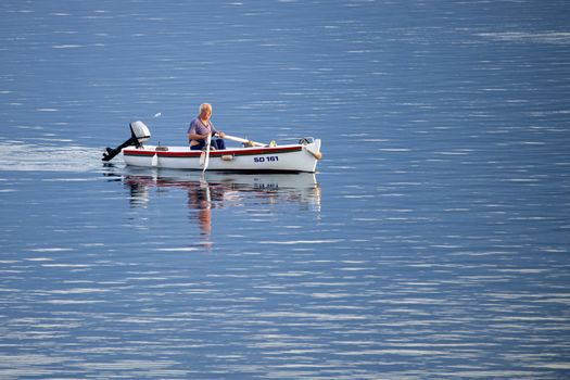 Old traditional fisherman in Croatia on a small wooden boat catching fish and rowing back into the harbor, authentic, not staged, early morning