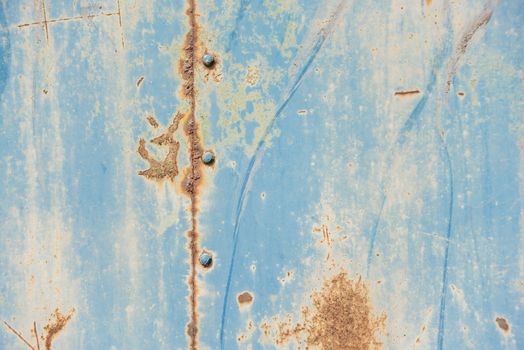 Grunge background: rusty metal surface covered with blue paint flaking and cracking texture, with seam and rivets