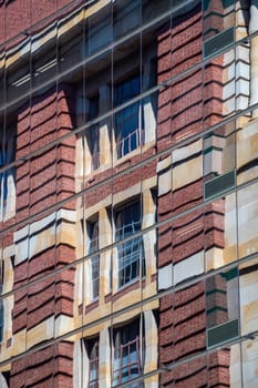 Reflection of brick building in modern skyscraper facade with reflective glassing