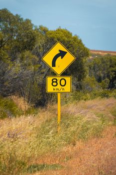 Street sign in Australia warning right curve ahead speed 80 in dry landscape