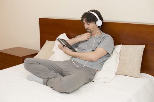 casual man working with a tablet pc in bed