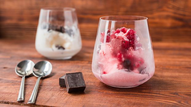 Sweet desert. White and pink ice cream in glass on wooden table.