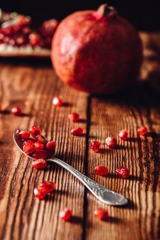 Pomegranate Seeds in Vintage Spoon. and Fruit on Backdrop.