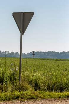 Road sign in countryside. Summer landscape with rural road, wood and cloudy blue sky. Classic rural landscape in Latvia.