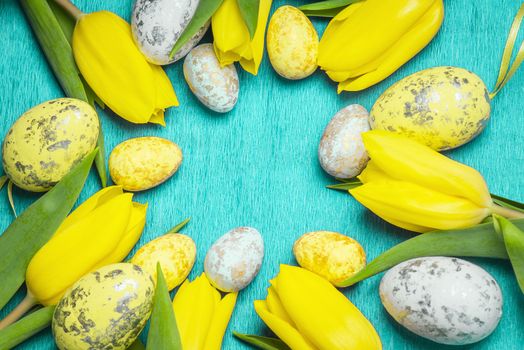 Happy Easter. Yellow fresh tulips lie on a blue background with Easter eggs.Happy Easter.