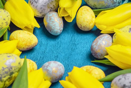 Happy Easter. Yellow fresh tulips lie on a blue background with Easter eggs.Happy Easter.