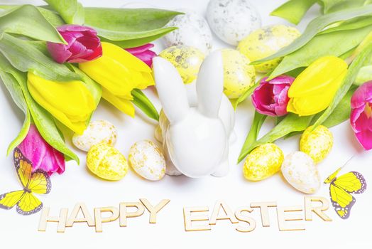 Easter white bunny on a white background with Easter eggs and fresh tulips.Easter greeting card with easter bunny. Easter eggs.Happy Easter.