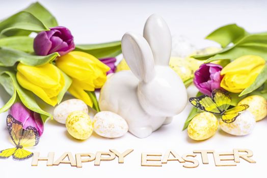 Easter white bunny on a white background with Easter eggs and fresh tulips.Easter greeting card with easter bunny. Easter eggs.Happy Easter.