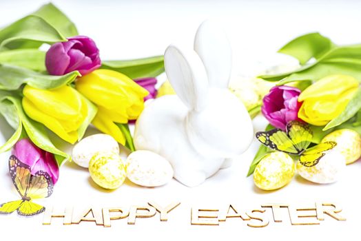 Easter white bunny on a white background with Easter eggs and fresh tulips.Easter greeting card with easter bunny. Easter eggs.Happy Easter.