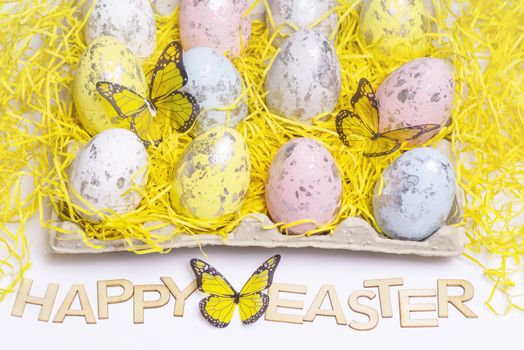 Happy Easter.Multi-colored Easter eggs on a white background with a bunch of wooden letters Happy Easter.