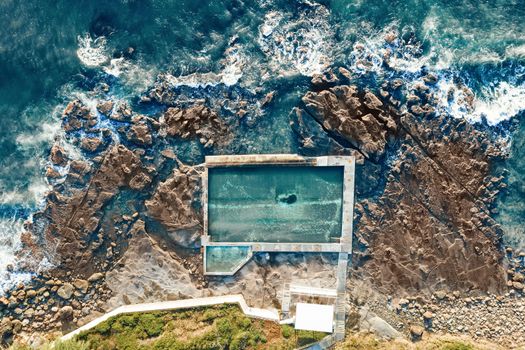 Coalcliff rock pool aerial shot. The pool sits on wht appears to be crumbling rocks surrounded by ocean