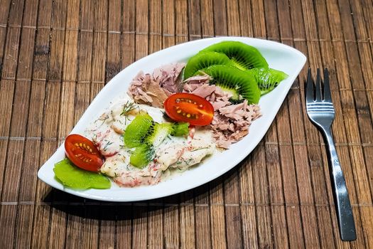 Healthy low-carbohydrate food in small bowl, lunch with tomatoes, tuna, kiwi, shrimp homemade sugar-free sauce.