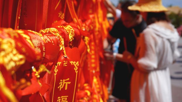 Two international tourists looking and reading through several ribbons with wishes. Tourists tied a red ribbon, China