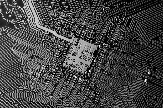 Close up photo of black and white printecd circuit board with solder points